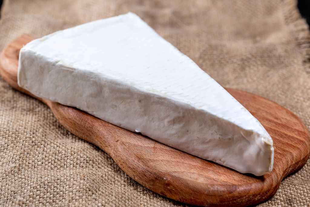 Dreieckige Form des Brie-Käses auf brauner Leinwand