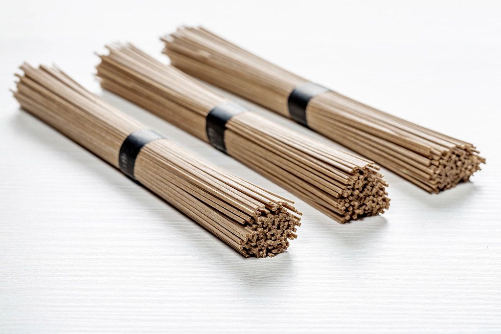 Dried raw Japanese soba noodle stick on white wooden background (Flip 2019)