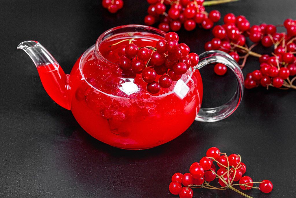 Sea buckthorn hot drink in a teapot with fresh berries on a black ...
