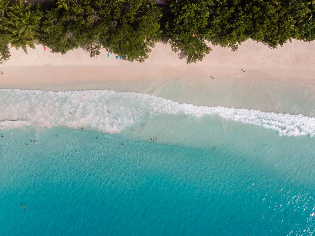 Drohnenbild vom türkisblauen Ozean und Strand Anse Lazio auf der Tropeninsel Praslin, Seychellen