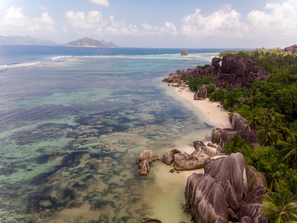 Drone picture of Anse Union Beach in La Digue, Seychelles, with its granite rock formations and palm trees in front of the Indian Ocean