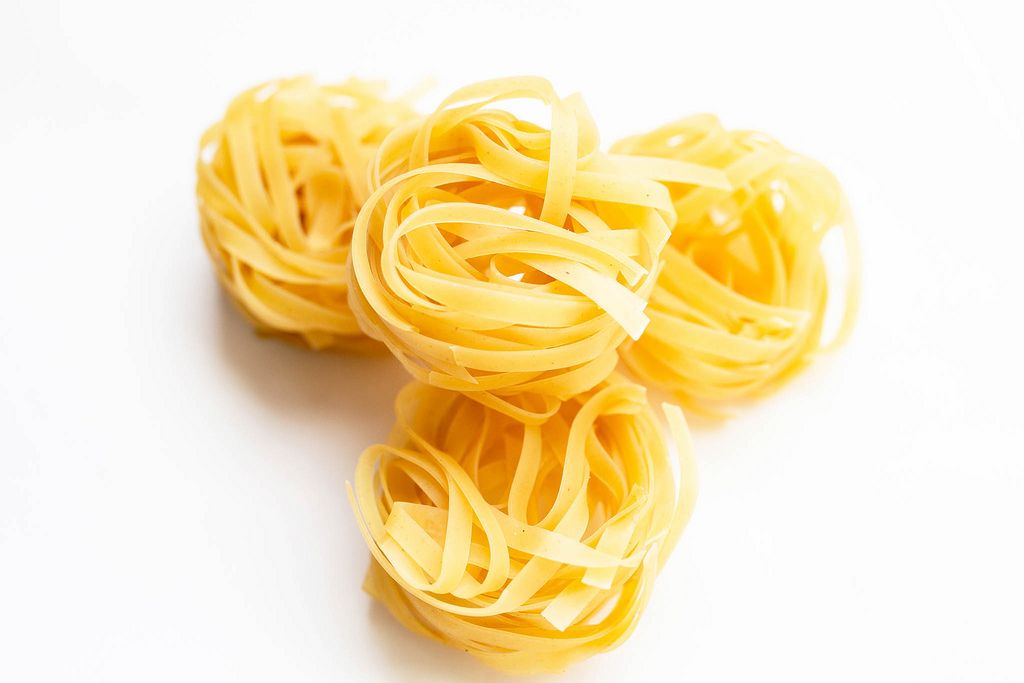 Dry tagliatelle pasta on white background (Flip 2019) (Flip 2019) Flip 2019