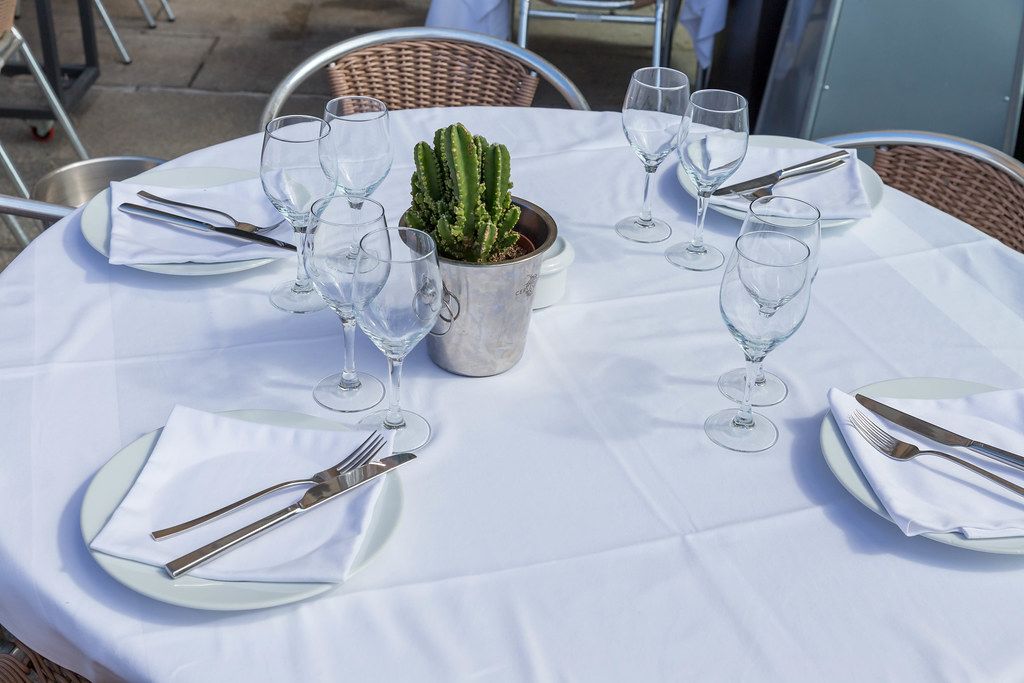 Edel gedeckter Tisch mit weißer Tischdecke, Servietten, Besteck, Gläsern und einem Kaktus in einem Restaurant in Barcelona, Spanien