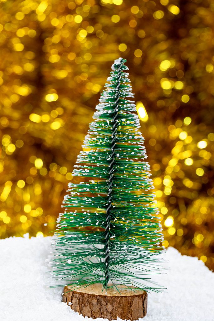 Ein dekorativer Weihnachtsbaum auf Schnee mit goldenem Lametta im Hintergrund