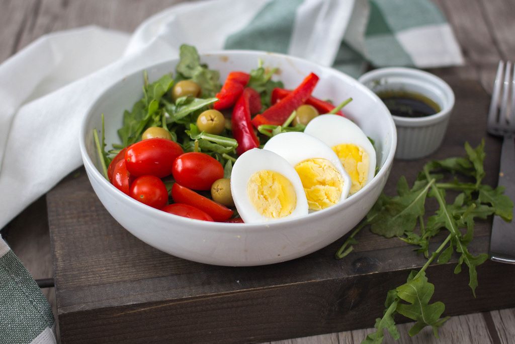Ein frischer Rucola-Ei Salat mit Oliven, Paprika und Tomaten