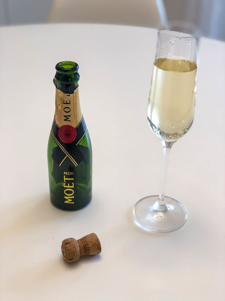 Ein Glas Champagner neben einer leeren Flaschen Mini Moët ...