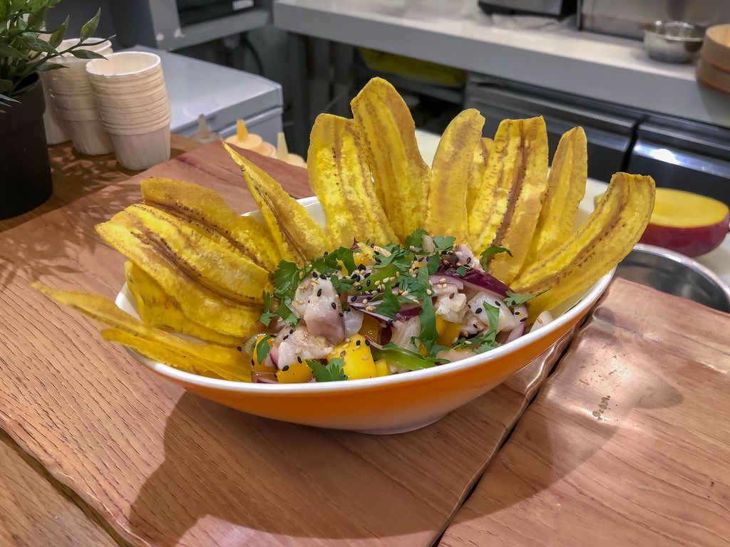 Ein Salat mit roten Zwiebeln und Ananasstücken mit Scheiben frittierter Bananen in einer Schüssel