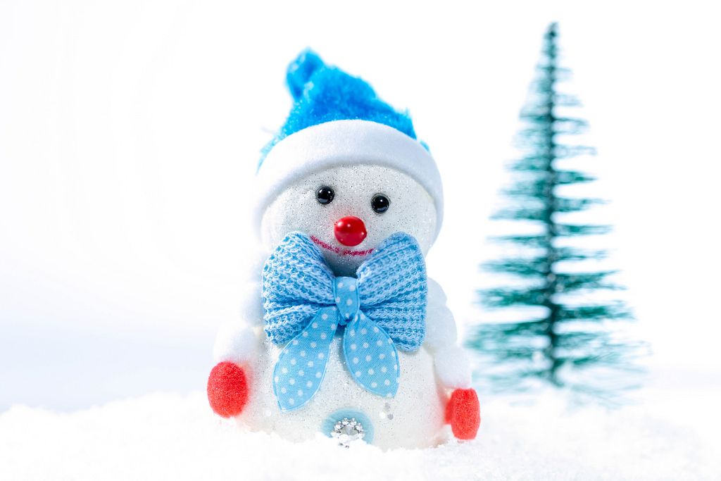 Ein Schneemann mit einer blauen Mütze und einer blauen Fliege im Schnee