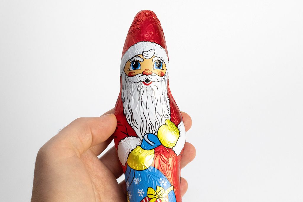 Ein Schokoladen-Weihnachtsmann in der Hand eines Mannes auf weißem Hintergrund