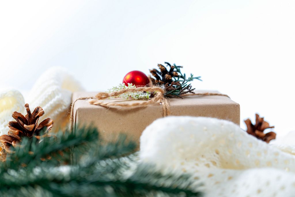Ein Weihnachtsgeschenk mit roter Christbaumkugel mit einer weißen Strickdecke