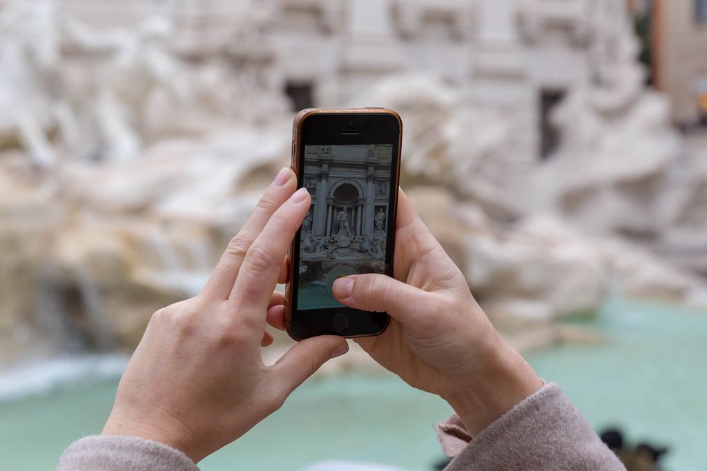 Eine Frau macht ein Foto mit dem Smartphone am Palazzo di Venezia in Rom
