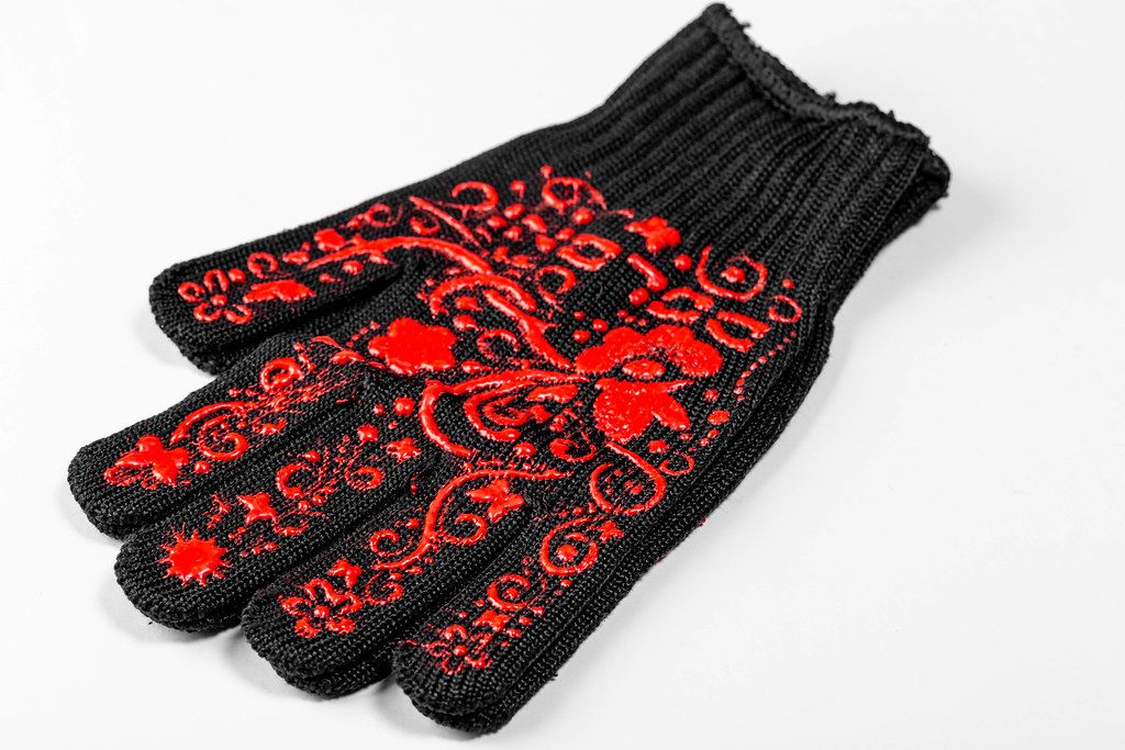 Einzelner Handschuh in schwarz mit rotem Blumen-Muster, auf weißem Hintergrund