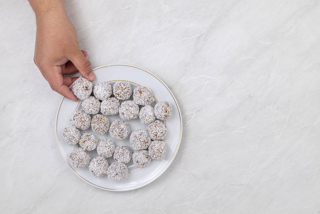 Energy Balls with Coconut in the hand above the table
