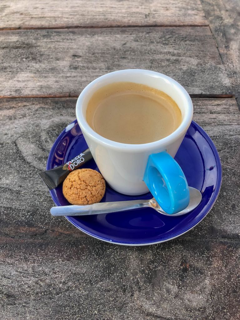 Espresso mit Zucker und Amaretti auf blauer Untertasse auf Holztisch