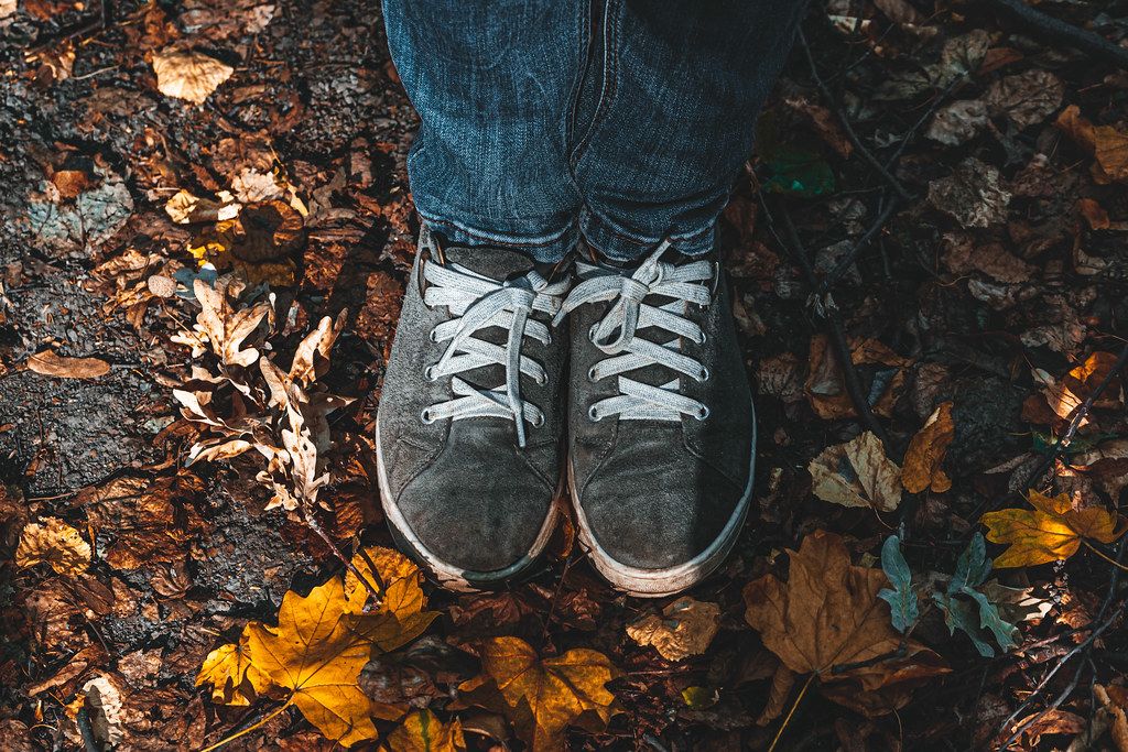 Feet in shoes on fallen dry leaves