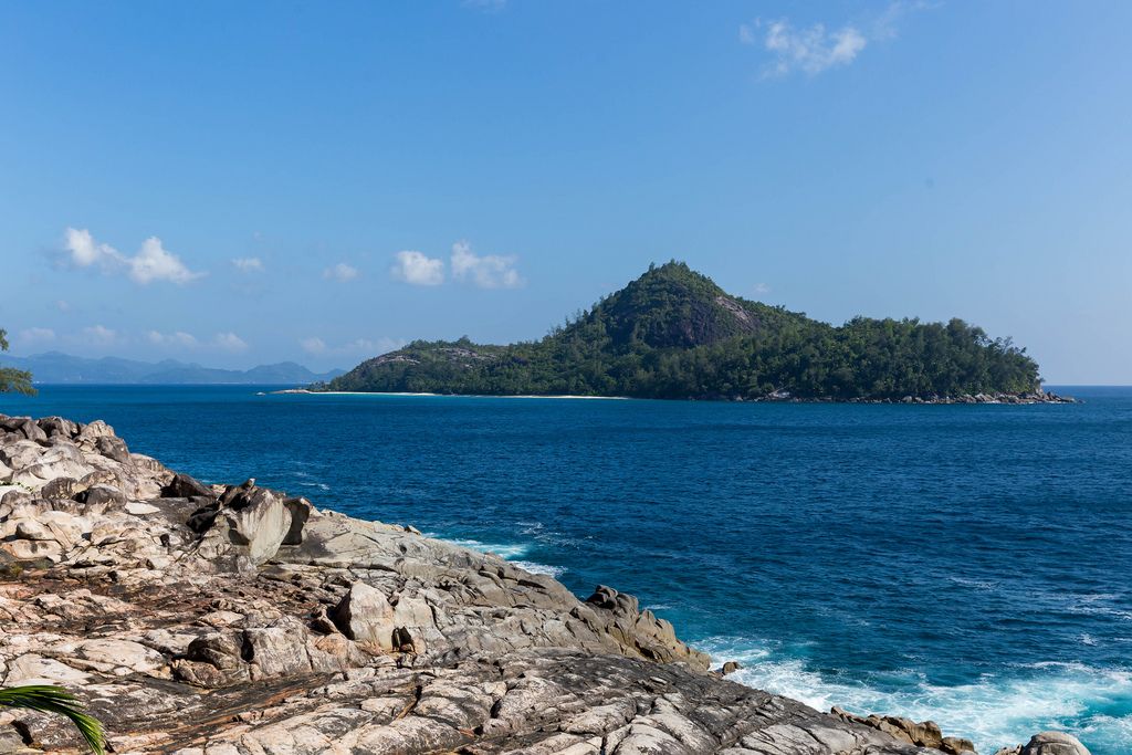 Felsenküste auf Mahé, nahe Anse des Anglais mit Blick auf die Seychellen-Insel Thérèse im Indischen Ozean