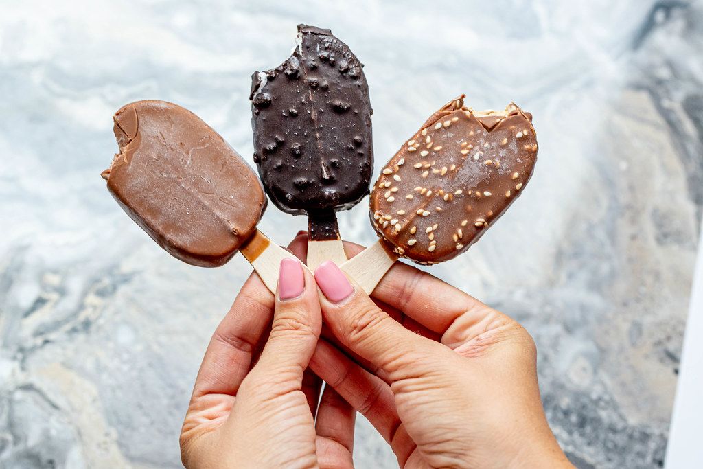 Female hands holding three bitten different chocolate ice cream