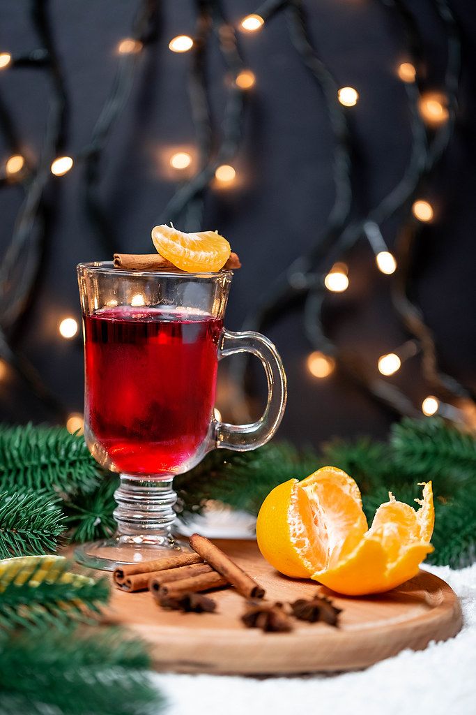 Festive mood with a warm Christmas drink: mulled wine with tangerine and cinnamon on a round wooden serving plate