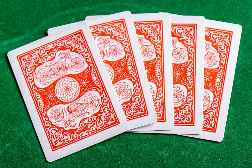 Five cards are laid out on a green background to start the game. The concept of gambling (Flip 2019)