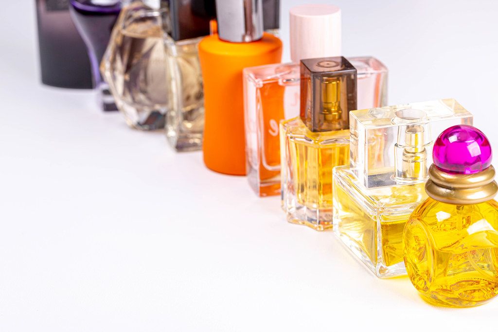 Flakons und Glasflaschen mit verschiedenem Parfüm gefüllt, in einer Reihe vor weißem Hintergrund