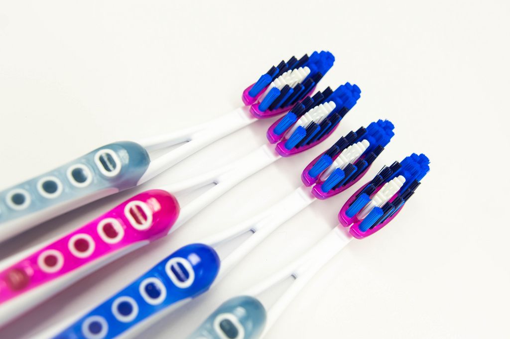 Four brand new toothbrushes on a white surface