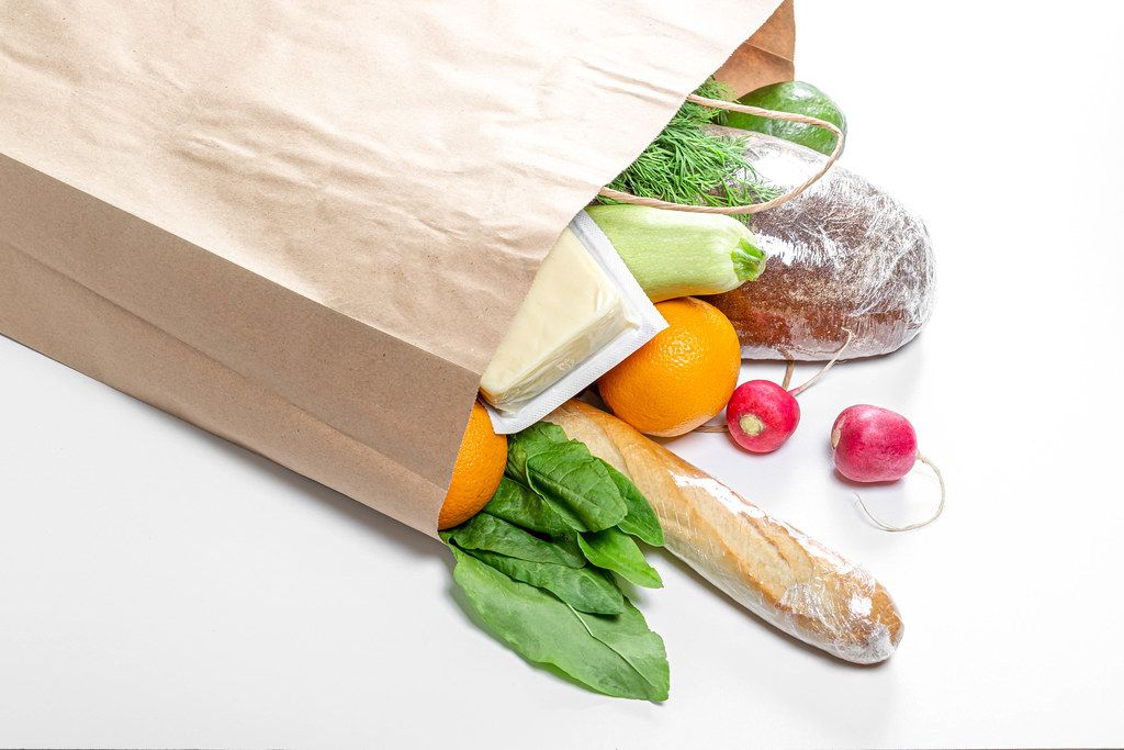 Fresh food on a white background in an open paper bag