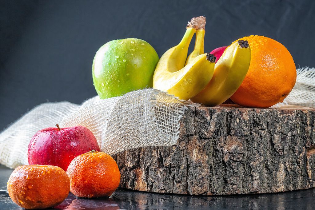 Fresh fruit with wooden stump and burlap on black table