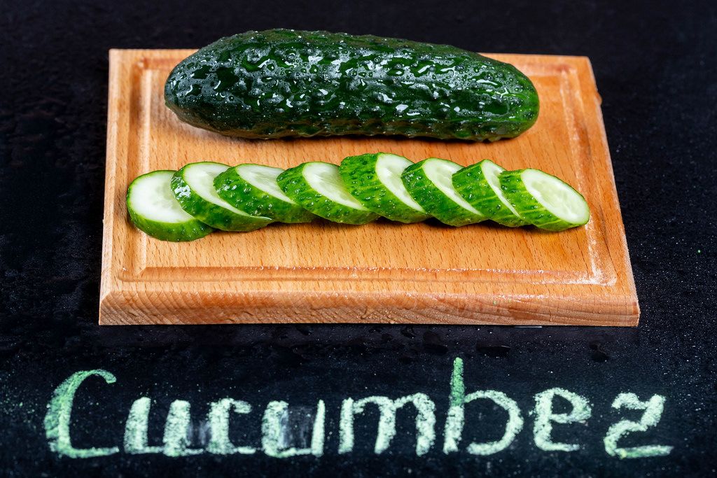 Fresh green cucumber with water drops and inscription