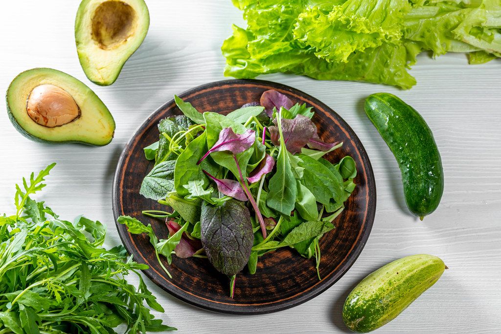 Fresh leaves assorted lettuce, spinach, arugula with avocado and cucumbers. Ingredients for a healthy diet