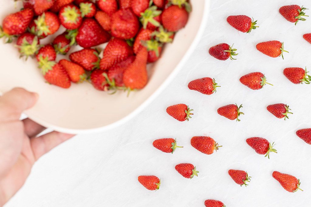 Fresh strawberries with blurred strawberries in the bowl