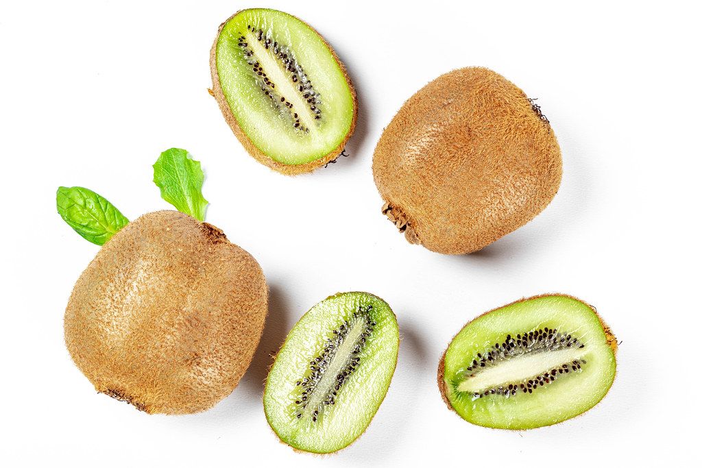 Fresh whole and slices of kiwi on a white background, top view