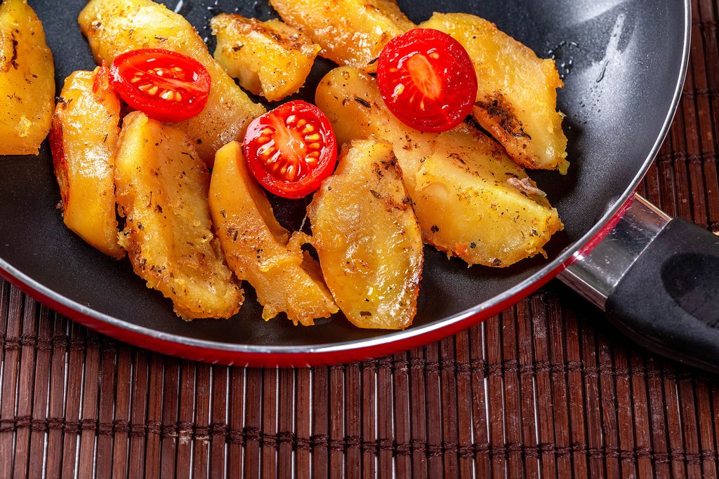 Fried potatoes in a frying pan with cherry tomatoes