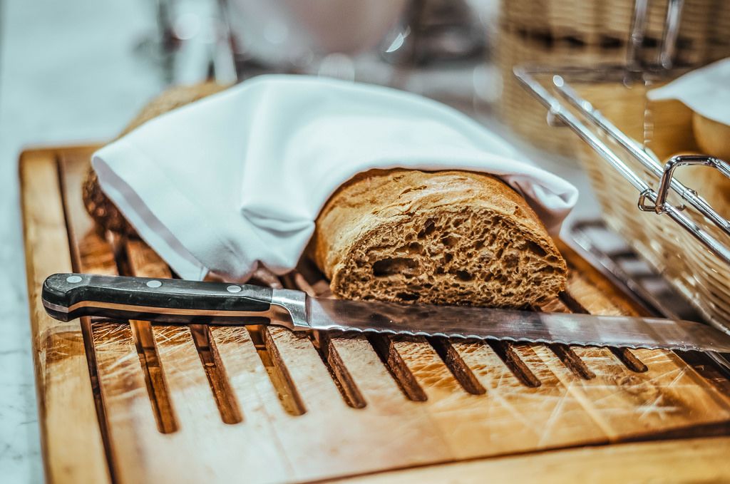 Frisches Brot mit Bitter und einem Messer auf einem Brettchen ...