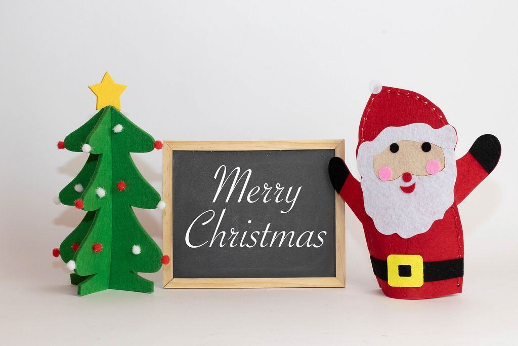 Frohe Weihnachten geschrieben auf einer Tafel mit einem Weihnachtsbaum und Weihnachtmann