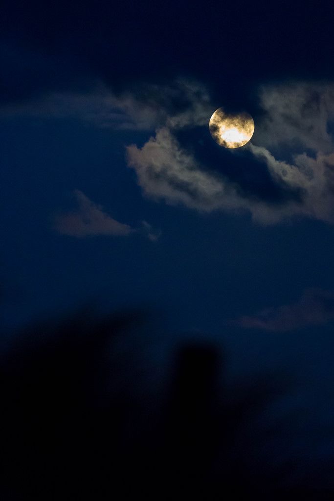 Full moon behind a thin layer of clouds