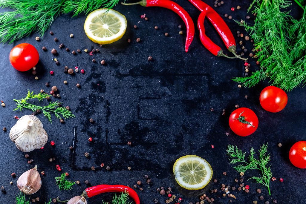 Garlic, lemon, dill and spices with cherry tomatoes on a dark background
