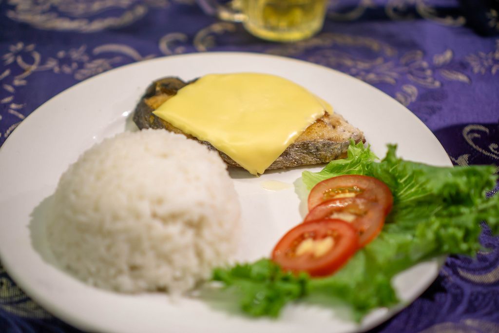 Gegrilltes Stück Fisch bedeckt mit Käse, dazu Reis zum Abendessen in Mui Ne, Vietnam