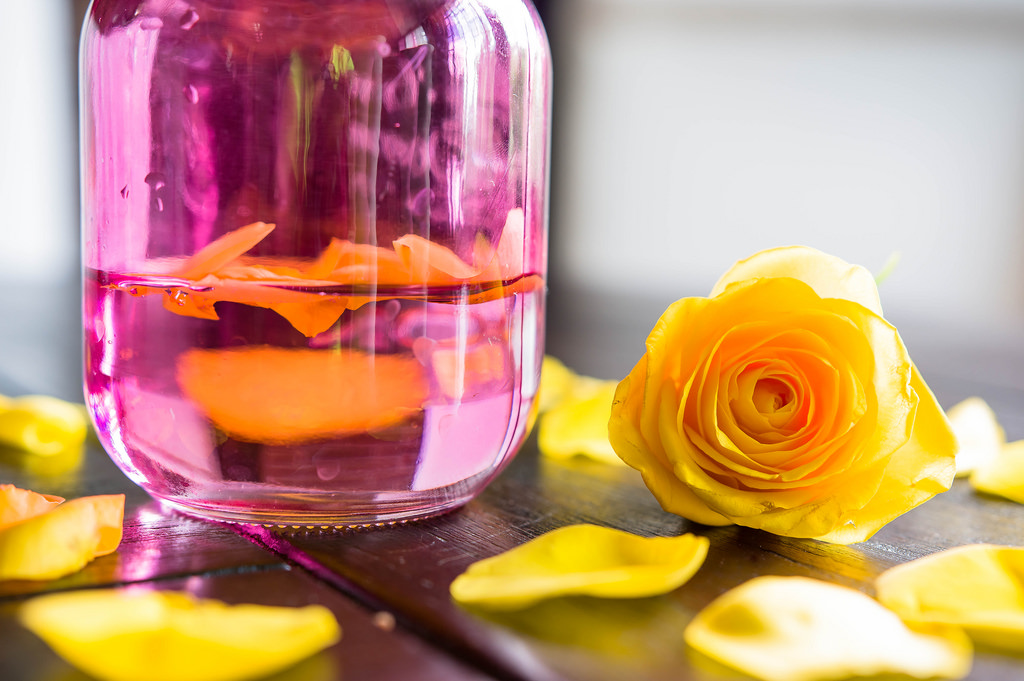 Gelbe Rosenblätter in einem rosafarbenen Glas