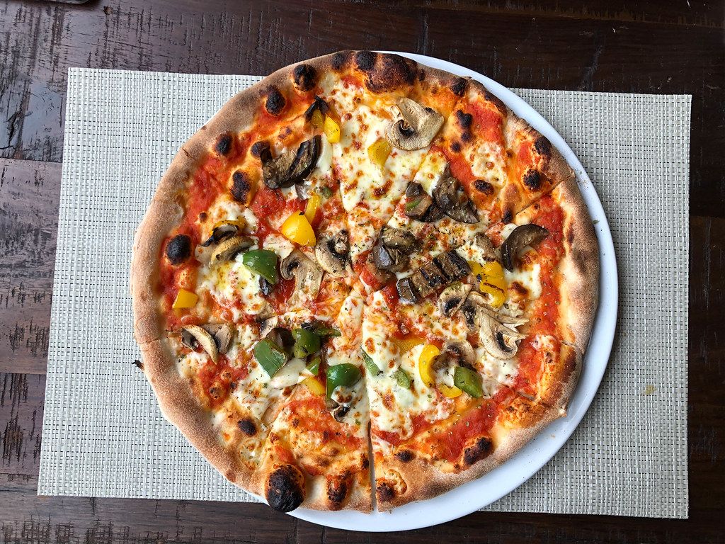 Geschnittene, vegetarische Pizza mit Gemüse und Pilzen, aus der Sicht von oben