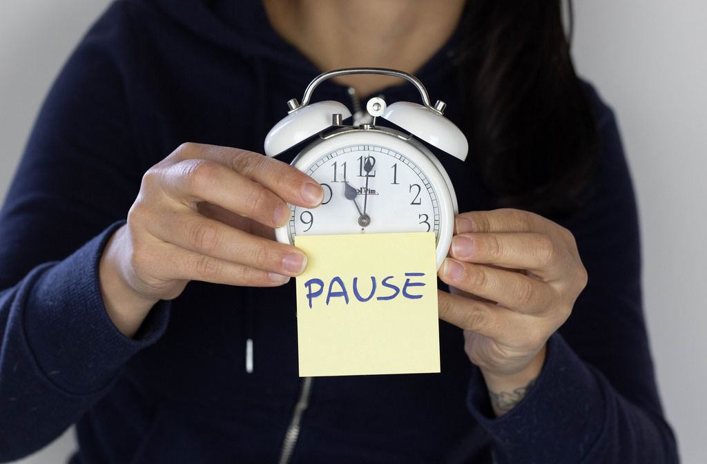 Girl holding a clock with pause note