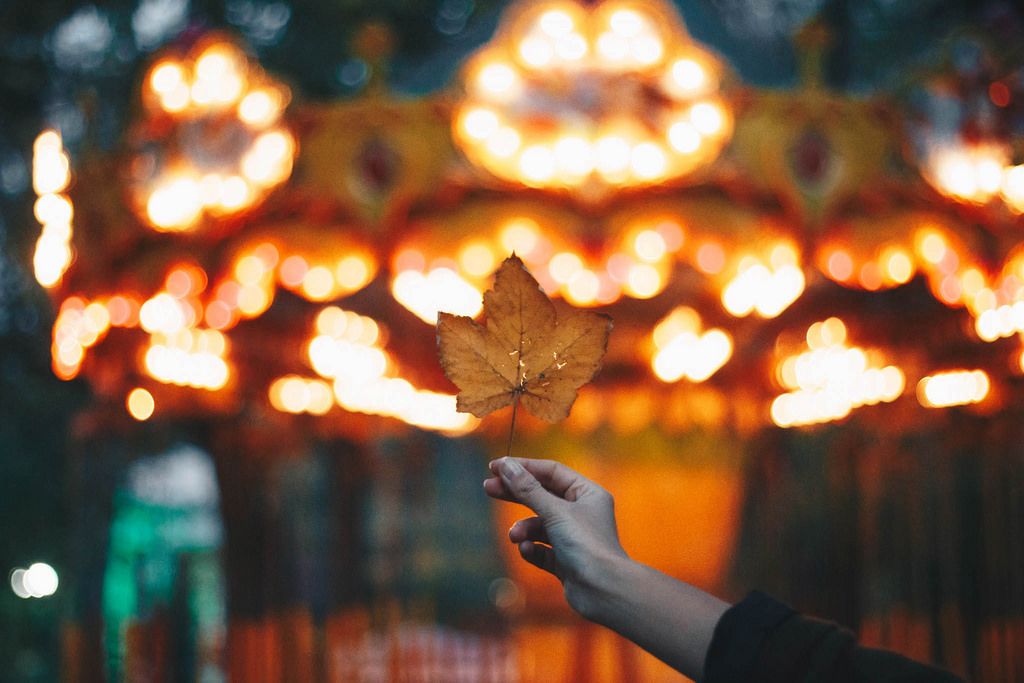 Girl holding a leaf on colorful blurry background. Autumn idea.