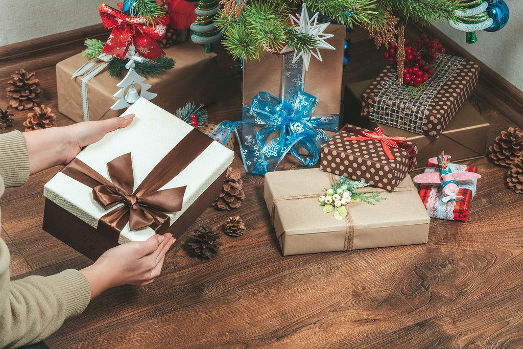 Girl puts gifts under the Christmas tree in the living room