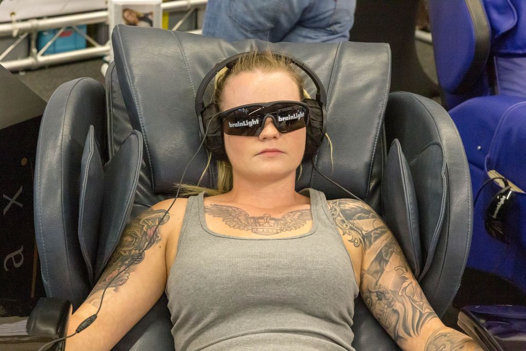 Girl relaxes in a Shiatsu-Massage Chair by brainLight to get deep physical regeneration at Fibo fitness trade show in Cologne