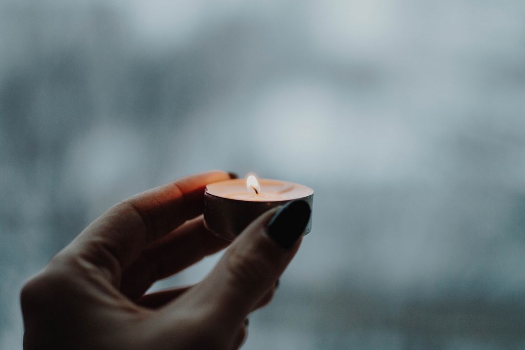 Girl's hand holding burning candle. Winter background.