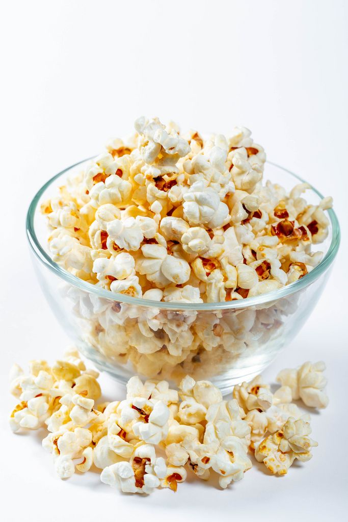 Glass bowl with popcorn on white background
