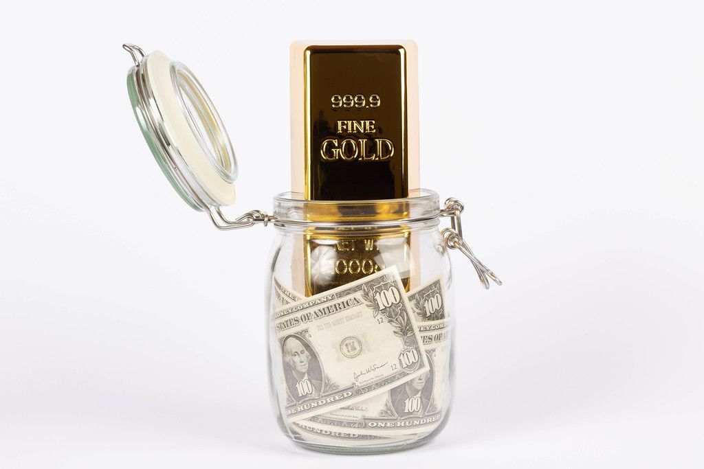 Gold bar in glass jar with money