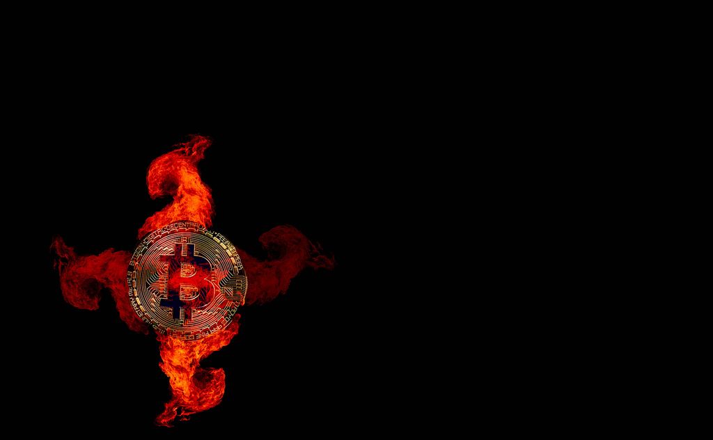 Golden Bitcoin in fire flames on black background