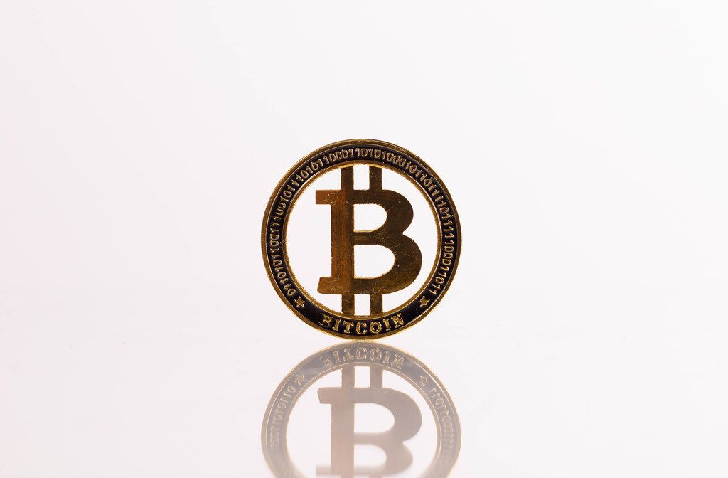 Golden Bitcoin with reflection on white background