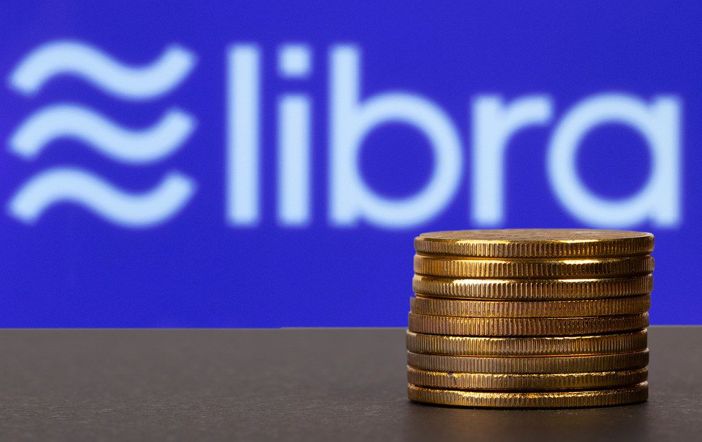Golden coins stacked in front of Libra cryptocurrency logo