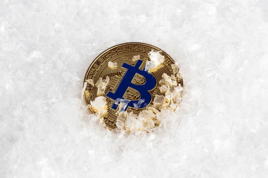Goldener Bitcoin im Schnee steht für Eiszeit der Kyptowährungen